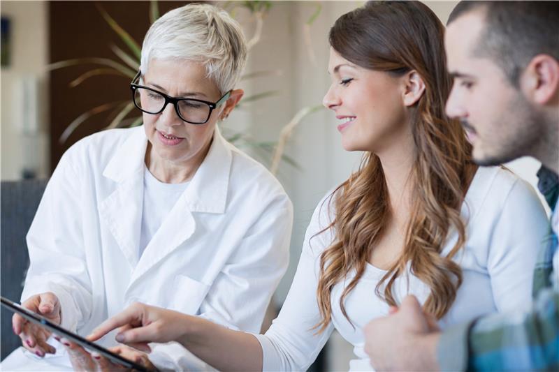 Female doctor with a heterosexual couple looking at a digital screen
