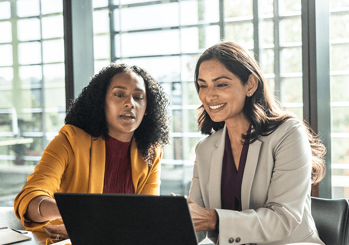 Two women looking at a laptop screen and chatting